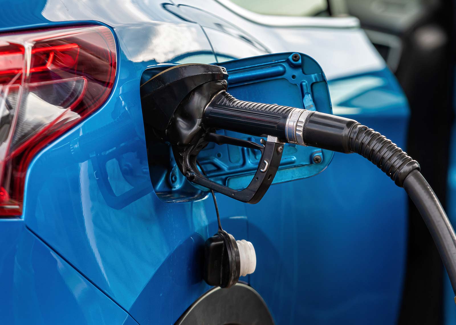 Blaues Auto tankt an Zapfsäule