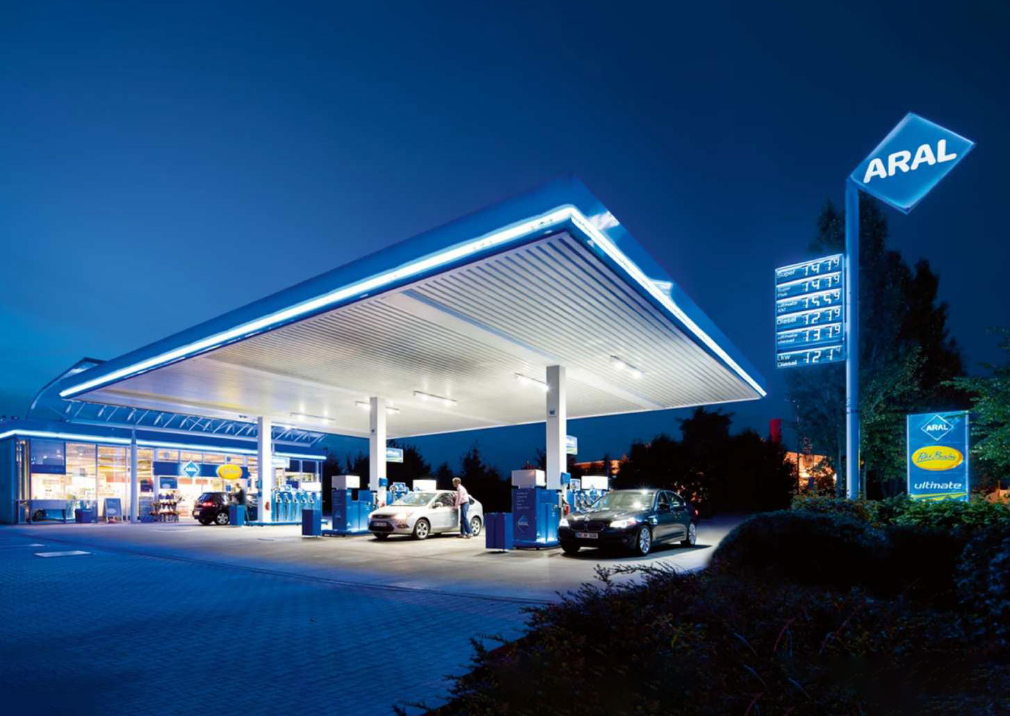 Beleuchtete Tankstelle bei Nacht mit Autos