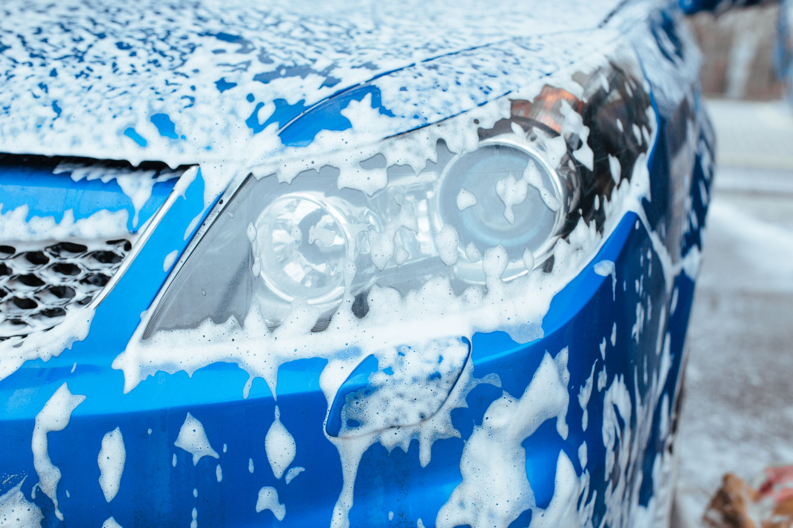 Blaues Auto mit Seifenschaum bei Autowäsche