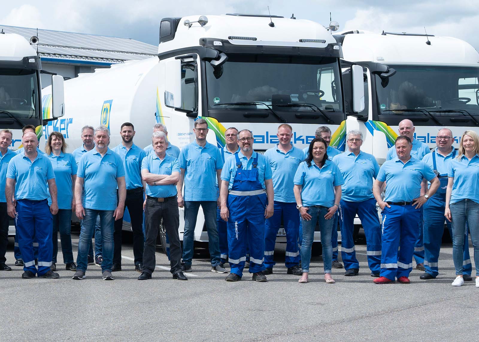 Team vor weißen Lastwagen in blauer Arbeitskleidung