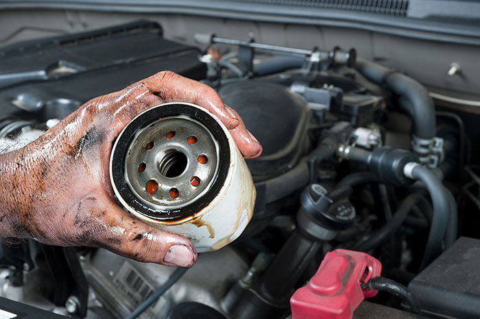 Mechaniker wechselt verschmutzten Ölfilter im Auto