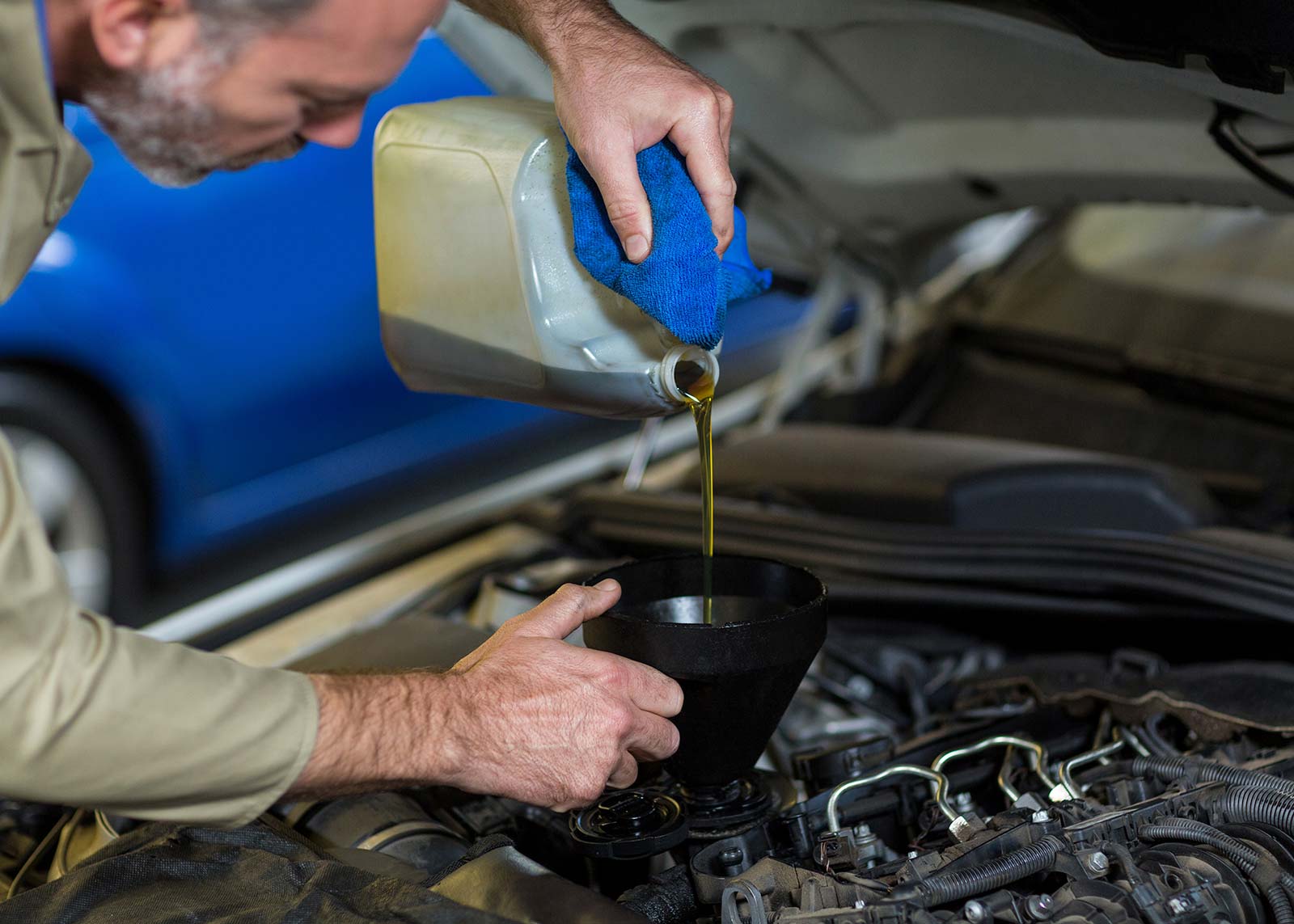 Mechaniker füllt Motoröl in Auto
