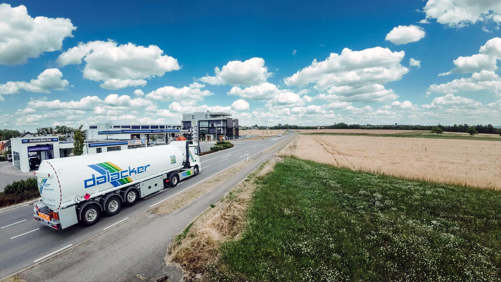 Tanklastwagen fährt auf Landstraße neben Getreidefeld